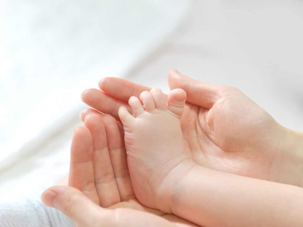Baby feet in mother hands. Mom and her Child. Happy Family concept. Beautiful conceptual image of Maternity